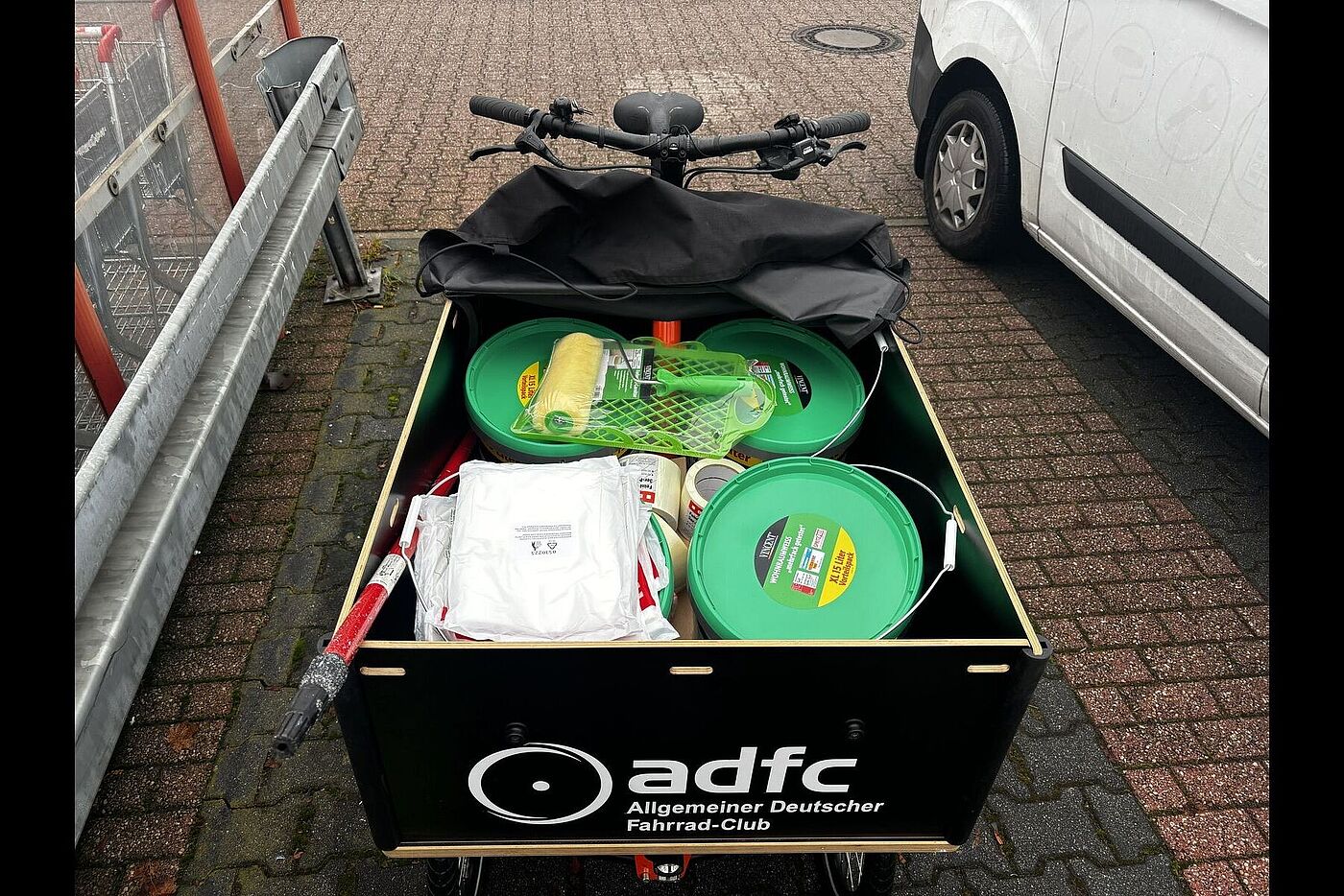 Große Transportbox eines ADFC-Lastenrads, gefüllt mit Farbeimern, Rollen und weiterem Malerbedarf.